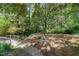 Lush backyard with mature trees, stone pathway, and a charming wooden bridge at 1416 Dunbar Ct, Cary, NC 27511