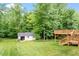 Picturesque backyard with shed and wooden deck, surrounded by mature trees and manicured lawn at 1614 Finnsbury Dr, Burlington, NC 27217