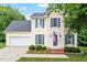 Charming two-story home featuring blue shutters, a well-manicured lawn, and an attached two-car garage at 1614 Finnsbury Dr, Burlington, NC 27217