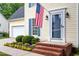 Close-up view of the home's front porch showcasing a blue door, an American flag, and brick steps at 1614 Finnsbury Dr, Burlington, NC 27217