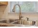 A stainless steel sink in front of a window and tiled backsplash, with faucet, soap dispenser and granite countertop at 1614 Finnsbury Dr, Burlington, NC 27217