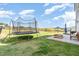 Backyard with a trampoline, stone patio, outdoor seating, grill, and views of a grassy hill under a bright sky at 19 Cecina Ct, Clayton, NC 27527