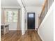 Bright entryway features hardwood floors, staircase with black iron spindles, and access to a sliding barn door at 19 Cecina Ct, Clayton, NC 27527