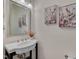 Well-lit powder room featuring a pedestal sink, modern faucet, decorative mirror, and floral wall art at 1904 Birdhouse Ln, Wake Forest, NC 27587