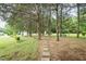 Lush backyard with mature trees, a charming swing, and a stone pathway adding character at 201 E Laramie Dr, Mebane, NC 27302