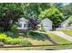 Lovely home featuring mature trees, a detached garage, flowering plants, and a stone staircase up to the driveway at 203 Needle Park Dr, Cary, NC 27513