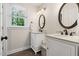 Dual sink bathroom with white cabinets, granite counters, round mirrors, and natural lighting from a window at 206 Kettlebridge Dr, Cary, NC 27511