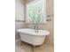 Traditional claw foot tub with tile surround and large window with blinds at 206 Kettlebridge Dr, Cary, NC 27511