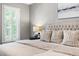 Relaxing primary bedroom featuring tufted headboard, decorative pillows, and window with plantation shutters at 206 Kettlebridge Dr, Cary, NC 27511