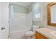 Bathroom with a wooden-framed mirror, white sink, toilet, and shower-tub with a curtain at 207 N Hopkins Ave, Spring Hope, NC 27882