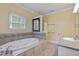 Bright bathroom featuring a jetted tub, tiled surround, and a gray vanity at 207 N Hopkins Ave, Spring Hope, NC 27882