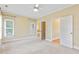 Well-lit bedroom with neutral carpet, ceiling fan, and two open doorways at 207 N Hopkins Ave, Spring Hope, NC 27882
