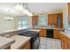 Well-lit kitchen with wooden cabinets, tile floors, and a black gas stove and oven range at 207 N Hopkins Ave, Spring Hope, NC 27882