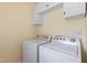 Well-lit laundry room featuring a white washer and dryer beneath white cabinets at 207 N Hopkins Ave, Spring Hope, NC 27882