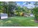 Spacious backyard featuring a large lawn, mature trees, and a view of the home and shed at 241 E Cornwall Rd, Cary, NC 27511