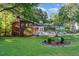 Lush backyard with well-maintained lawn, mature trees, brick home exterior, and outdoor patio area at 241 E Cornwall Rd, Cary, NC 27511