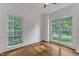 Bonus room or office featuring hardwood floors, white walls, a ceiling fan, and two large windows at 2513 Myrtle Ln, Hillsborough, NC 27278
