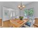 Dining room featuring wood floors, white walls, a modern chandelier, and a large window for natural light at 2513 Myrtle Ln, Hillsborough, NC 27278
