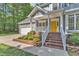Up close view of a charming home with a yellow front door, lush landscaping, and a brick staircase at 2513 Myrtle Ln, Hillsborough, NC 27278