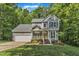 Charming two-story home with a yellow front door, lush landscaping, and a two car garage nestled amongst mature trees at 2513 Myrtle Ln, Hillsborough, NC 27278