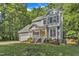Two-story home with gray siding, lush landscaping and a bright yellow front door surrounded by mature shade trees at 2513 Myrtle Ln, Hillsborough, NC 27278