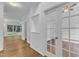 Hallway with hardwood floors leading to various rooms, including a room enclosed with glass doors at 2513 Myrtle Ln, Hillsborough, NC 27278