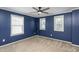 This bedroom features three windows, a modern ceiling fan and freshly painted blue walls at 310 Seymour Pl, Cary, NC 27519