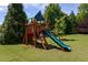 Wooden playground with a slide and swing set sits on a lush green lawn, perfect for Gathering fun at 310 Seymour Pl, Cary, NC 27519