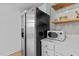 Close-up of the kitchen, highlighting stainless steel refrigerator and microwave on white countertop with wooden shelving at 320 W Martin St # 205, Raleigh, NC 27601