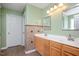 Bathroom featuring a double vanity with wood cabinets, light green walls, and neutral tiling at 3566 Sunbright Ln, Raleigh, NC 27610
