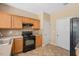 Efficient kitchen with black appliances, light wood cabinets, and practical tile flooring at 3566 Sunbright Ln, Raleigh, NC 27610