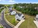 An aerial view showcases a charming white farmhouse-style home surrounded by lush trees in a peaceful neighborhood at 386 The Parks Dr, Pittsboro, NC 27312