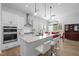 Modern white kitchen with stainless steel appliances, quartz countertops, and an island with bar seating at 386 The Parks Dr, Pittsboro, NC 27312