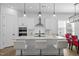 Bright, white kitchen featuring a center island with bar stools and stainless steel appliances at 386 The Parks Dr, Pittsboro, NC 27312