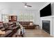 Spacious living room with fireplace, mounted TV, wood flooring, and comfortable leather seating at 386 The Parks Dr, Pittsboro, NC 27312