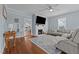 Bright living room featuring a painted fireplace, mounted TV, hardwood floors, and a view into the kitchen at 404 W E St, Erwin, NC 28339