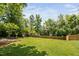 Spacious backyard with a large grassy area, privacy fence, and mature trees at 4404 Yadkin Dr, Raleigh, NC 27609