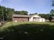 Beautifully manicured backyard with lush green grass and a charming view of the brick home at 4908 Mandel Rd, Durham, NC 27712