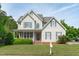 Charming two-story home featuring a welcoming front porch, blue shutters, and beautifully maintained landscaping at 6002 Whisperwood Dr, Durham, NC 27713