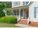 Inviting covered front porch with brick steps, white railings, and a view of the landscaped front yard at 6002 Whisperwood Dr, Durham, NC 27713