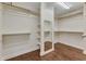 Spacious walk-in closet with wood floor, installed shelves, and a large mirror at 644 Angelica Cir, Cary, NC 27518
