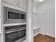 Close-up view of built-in stainless steel microwave and oven, with a small bench and cabinet storage at 644 Angelica Cir, Cary, NC 27518