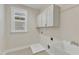 Convenient laundry room features utility sink, storage cabinets, and tile floor at 644 Angelica Cir, Cary, NC 27518