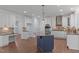 Spacious kitchen featuring white cabinets, a blue island, stainless appliances, and hardwood floors at 6509 Duncans Creek Ct, Fuquay Varina, NC 27526