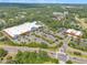 An aerial view showcasing a shopping center, a large parking lot, and surrounding green spaces with roads and light traffic at 711 Providence Glen Dr, Chapel Hill, NC 27514