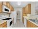 Functional kitchen featuring wooden cabinets, white appliances, and tile flooring for a clean and efficient cooking space at 711 Providence Glen Dr, Chapel Hill, NC 27514