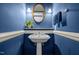 Stylish blue powder room featuring a pedestal sink, decorative mirror, and elegant lighting at 74002 Harvey, Chapel Hill, NC 27517