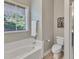 Bright bathroom with a large window and a tub with white tile surround at 8113 Huskfield Ct, Apex, NC 27539