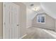 Carpeted bedroom with window into the eaves of the roof and a doorway in the shot at 8113 Huskfield Ct, Apex, NC 27539