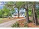 Beautiful home surrounded by mature trees, featuring a long driveway and attached garage at 8113 Huskfield Ct, Apex, NC 27539